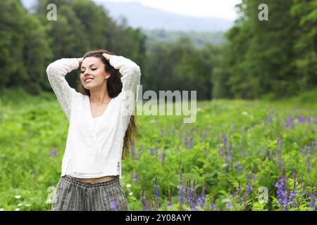 Felice bella bruna donna nel campo dei fiori, carino donna rilassata sul prato di fiori di primavera, natura, divertimento outdoor Foto Stock