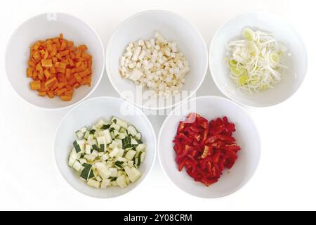 Diversi tipi di verdure tritate in ciotole bianche, preparazione della cottura Foto Stock
