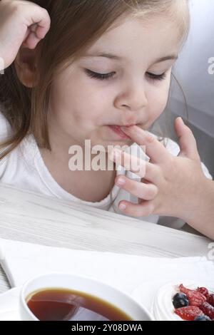 Poco carino ragazza mangiare Anna Pavlova cake Foto Stock