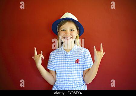 Piuttosto emothional bambini indossare un cappello su uno sfondo di colore rosso. Copia spazio, luce diurna Foto Stock