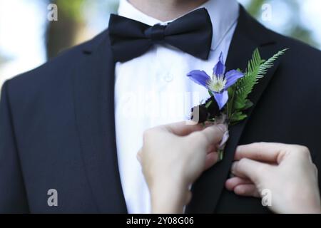 Primo piano della sposa boutonniere di regolazione con la clematide sulla camicia di sposi Foto Stock