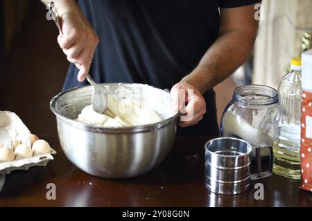 Mani maschio per impastare la pasta fresca sul tavolo della cucina. Close up Foto Stock