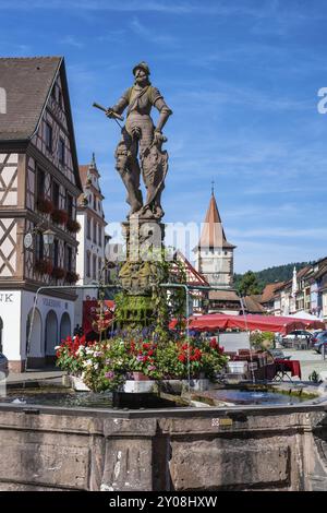 La fontana della piazza del mercato, Roehrbrunnen, con un cavaliere sullo scudo lo stemma della città, dietro di essa l'Obertorturm, Haigeracher Tor, città storica Foto Stock