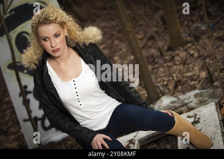 Giovane donna bionda con lunghi capelli ricci in un ambiente autunnale all'aperto Foto Stock