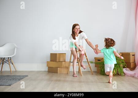 La famiglia felice a giocare nella nuova casa. Madre e figlia divertirsi insieme. Casa mobile di giorno e di esprimere il concetto di consegna Foto Stock