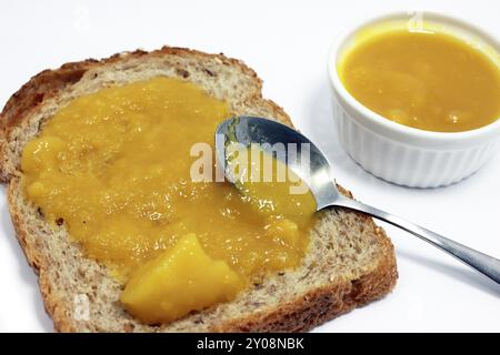 Pezzo di pane con marmellata di albicocche isolata su bianco Foto Stock