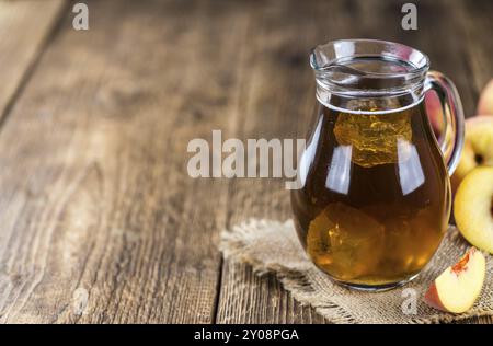 Tè ghiacciato (pesca) su un vecchio tavolo di legno (messa a fuoco selettiva, primo piano) Foto Stock