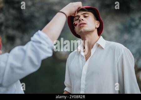 Giovane uomo che indossa un cappello rosso che si gode momenti all'aperto mentre un amico gli offre del cibo Foto Stock