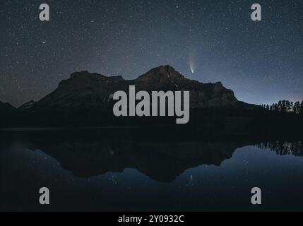 Cielo notturno con stelle sopra una montagna e il suo riflesso in un lago calmo, silhouette e una cometa visibile, Cometa NEOWISE, Kananaskis Country, Alberta, CA Foto Stock