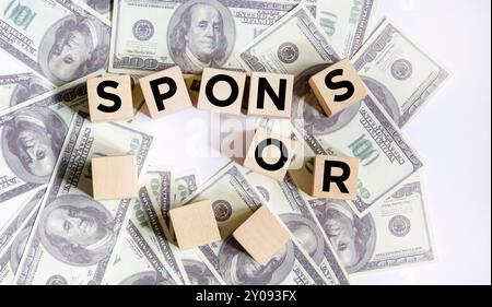 Blocchi di legno con SPONSOR scritto su banconote da un dollaro Foto Stock