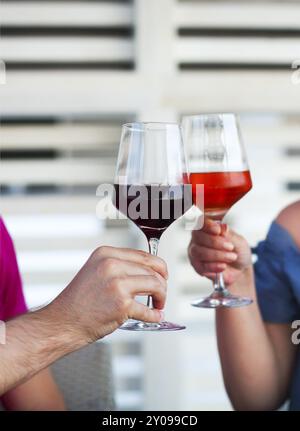 Due wineglasses di rosso e rosato nelle mani di un uomo e di una donna Foto Stock