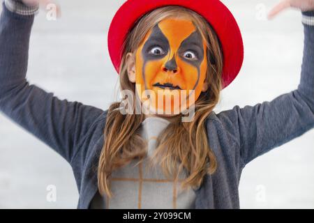 Bella bambina con la pittura del viso di una zucca. Tema di Halloween Foto Stock