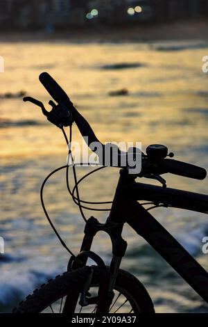 Silhouette of bicycle in front of the beach during sunset Stock Photo