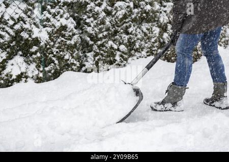 Donna che pulisce la neve sul marciapiede Foto Stock