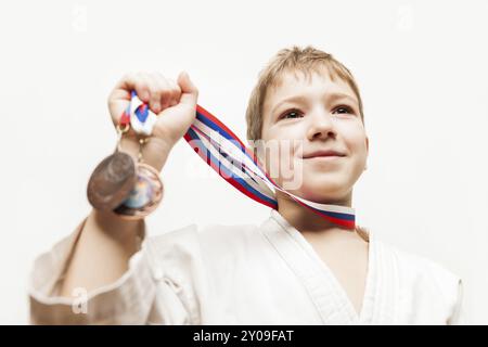 Arte marziale sport di successo e concetto di vittoria, campione di karate sorridente bambino ragazzo mano che tiene il primo posto vittoria medaglia d'oro Foto Stock