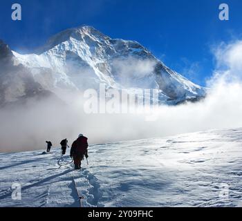 Gruppo di arrampicatori su corda sul ghiacciaio e sul Monte Makalu con nuvole, montagne Nepal Himalaya, valle di Barun Foto Stock