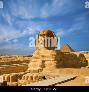 Profilo del corpo a tutta lunghezza della grande Sfinge con testa, piedi con grande piramide di Menkaure sullo sfondo in una giornata limpida e blu del cielo a Giza, Egitto emp Foto Stock