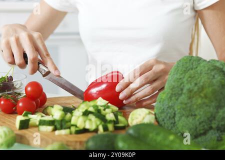 Le mani di una donna come tagliare le verdure in cucina Foto Stock