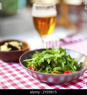 Un bicchiere di birra chiara con insalata del pub Foto Stock