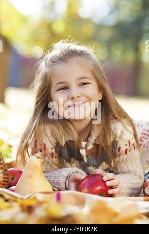 Adorabile bambina con le foglie di autunno e apple nel parco di bellezza Foto Stock