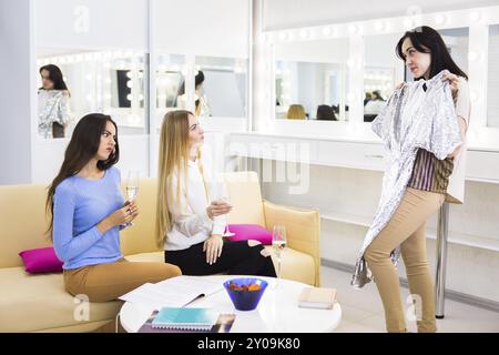 Amici di sesso femminile la scelta di abbigliamento insieme in un negozio di bere chmpagne Foto Stock