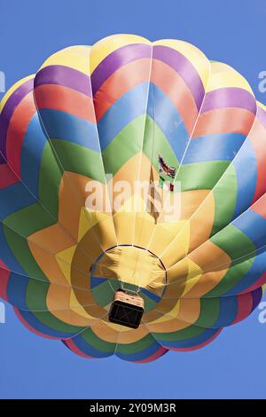 Colorato in mongolfiera in volo visto da sotto contro un cielo blu Foto Stock