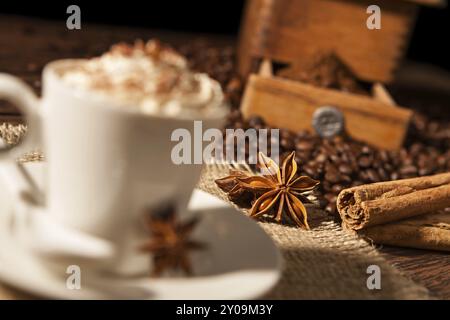 Close-up su anice stellato e bastoncini di cannella con tazza di caffè e panna montata Foto Stock