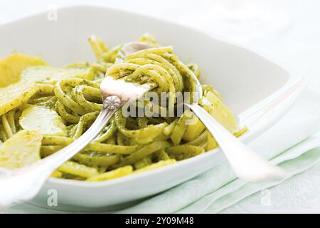 Primo piano di linguine con pesto genovese e patate su una tavola con posate Foto Stock