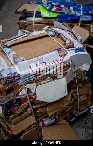 Riciclaggio di scatole di cartone - scatole di cartone usate piatte e raggruppate insieme pronte per la raccolta e il riciclaggio. Foto Stock