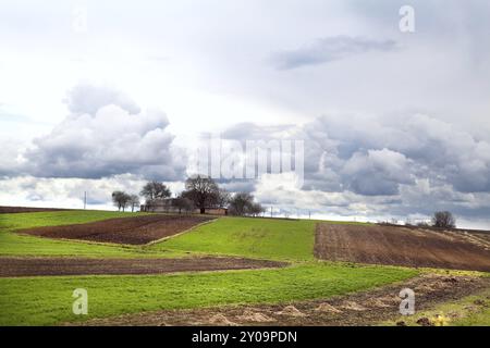 Ammira il villaggio tra campi arati e pascoli sopra il cielo nuvoloso Foto Stock