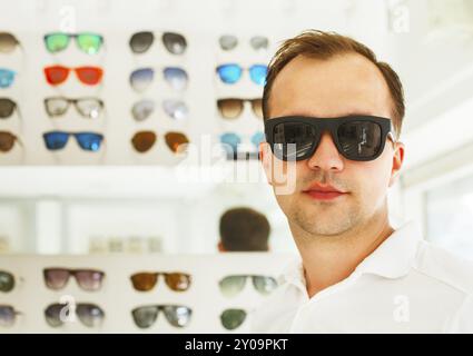 Ritratto di un uomo che cerca su nuovi occhiali da sole presso gli ottici Foto Stock