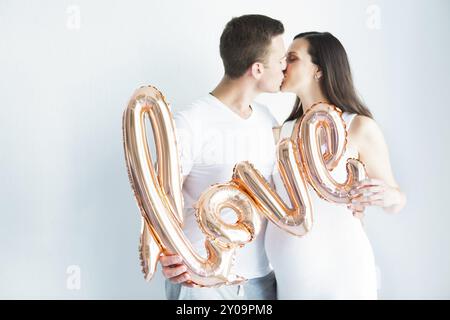 Felice giovane donna incinta e Uomo in amore su sfondo bianco. Amore e il concetto di famiglia Foto Stock