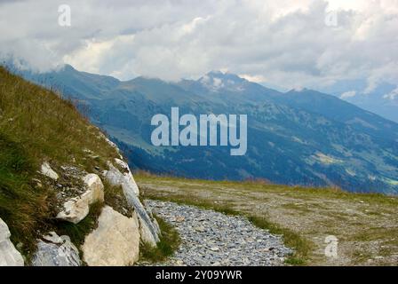 Vista di un incredibile paesaggio montano con un sentiero roccioso in una giornata nebulosa con nuvole grigie e nebbia sulle vette in autunno in Austria. Foto Stock