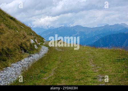 Vista di un incredibile paesaggio montano con un sentiero roccioso in una giornata nebulosa con nuvole grigie e nebbia sulle vette in autunno in Austria. Foto Stock