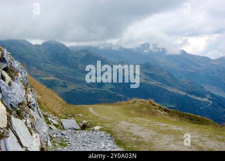 Vista di un incredibile paesaggio montano con un sentiero roccioso in una giornata nebulosa con nuvole grigie e nebbia sulle vette in autunno in Austria. Foto Stock