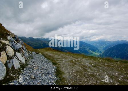 Vista di un incredibile paesaggio montano con un sentiero roccioso in una giornata nebulosa con nuvole grigie e nebbia sulle vette in autunno in Austria. Foto Stock