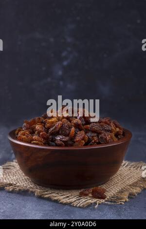 Primo piano della dolce uvetta marrone in una ciotola rustico sfondo scuro Foto Stock