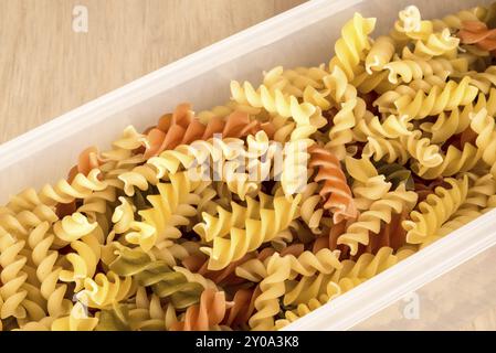 Tre diversi colori di fussili, visti dall'alto, mentre riempiono un contenitore di plastica bianco di forma lunga, stretta e quadrata Foto Stock