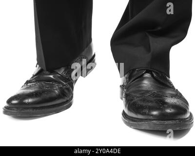 Abito maschile che indossa scarpe nere in avvicinamento verso il bianco Foto Stock