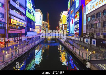 OSAKA, GIAPPONE, 23 GIUGNO 2015: Cartelli luminosi illuminati sulle rive del canale Dotonbori di notte nel quartiere Namba di Osaka, Giappone. Orizzontale Foto Stock