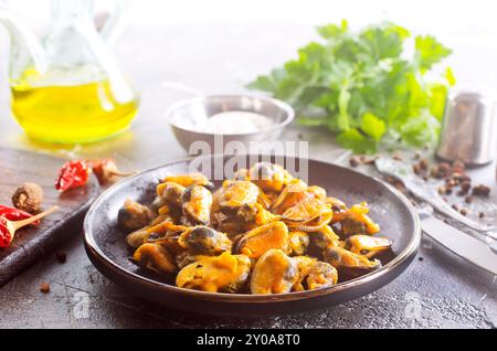 mescolare la cozze fritta piccante con la cipolla a fette e la spezia sul piatto Foto Stock