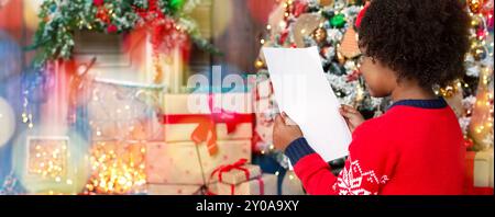 Preparazione per il Natale. Little Black girl holding vuota del foglio di carta Foto Stock