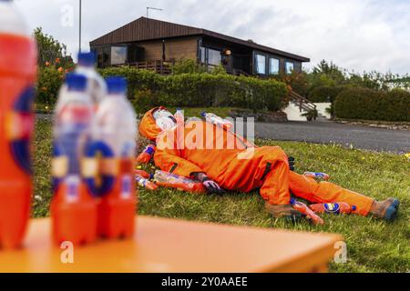 DJUPIVOGUR, ISLANDA, 21 GIUGNO: Manichino maschile giace sull'erba ricoperto di bottiglie di succo d'arancia il 21 giugno 2013 a Djupivogur, Islanda, Europa Foto Stock