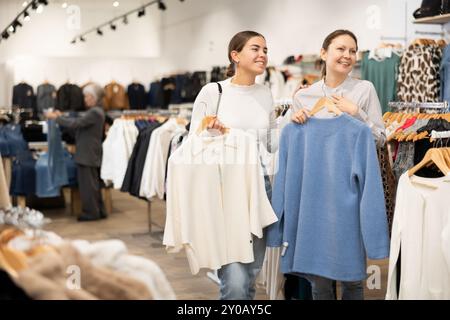 Due donne che scelgono un maglione comodo nel negozio di abbigliamento Foto Stock