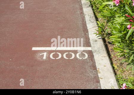 Linee bianche che indicano il punto di 1000 metri di una pista rossa Foto Stock