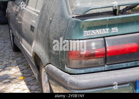 Primo piano di una renault 19 rti verde sporca parcheggiata su una strada acciottolata, mostrando la sua età e usura Foto Stock