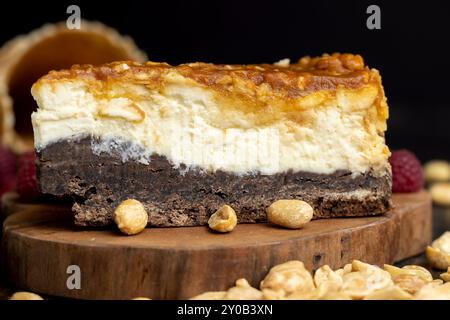 Cheesecake con pan di Spagna al cioccolato e arachidi al caramello, delizioso dessert con arachidi e crema di formaggio Foto Stock