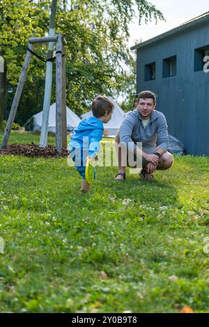 Padre e figlio giocano insieme su un prato erboso vicino a una casa Foto Stock