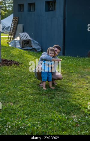 Padre e figlio giocano insieme su un prato erboso vicino a una casa Foto Stock