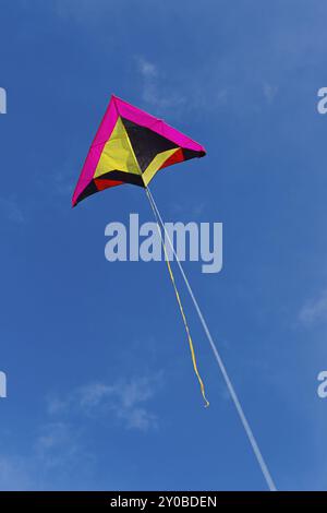 Un aquilone colorato che vola in alto nel cielo blu brillante Foto Stock